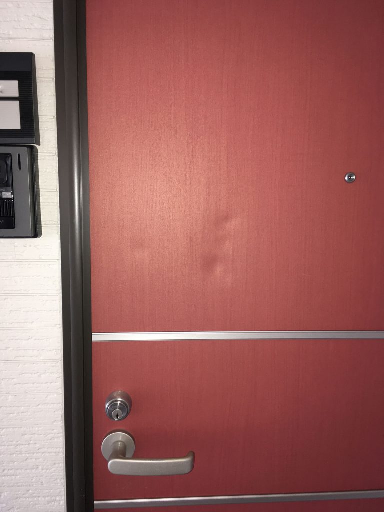 玄関扉の凹みのシート貼付けによる修理